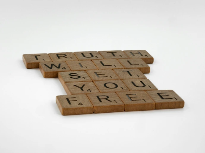 three scrabble tiles spelling truth and truth